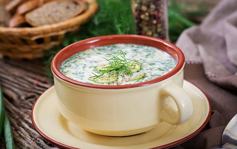 Summer yogurt cold soup with egg, cucumber, and dill on wooden table. Okroshka. Russian food